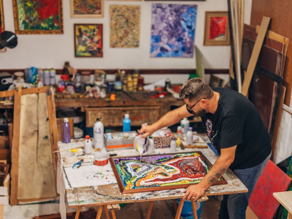 A painter pouring paint on canvass