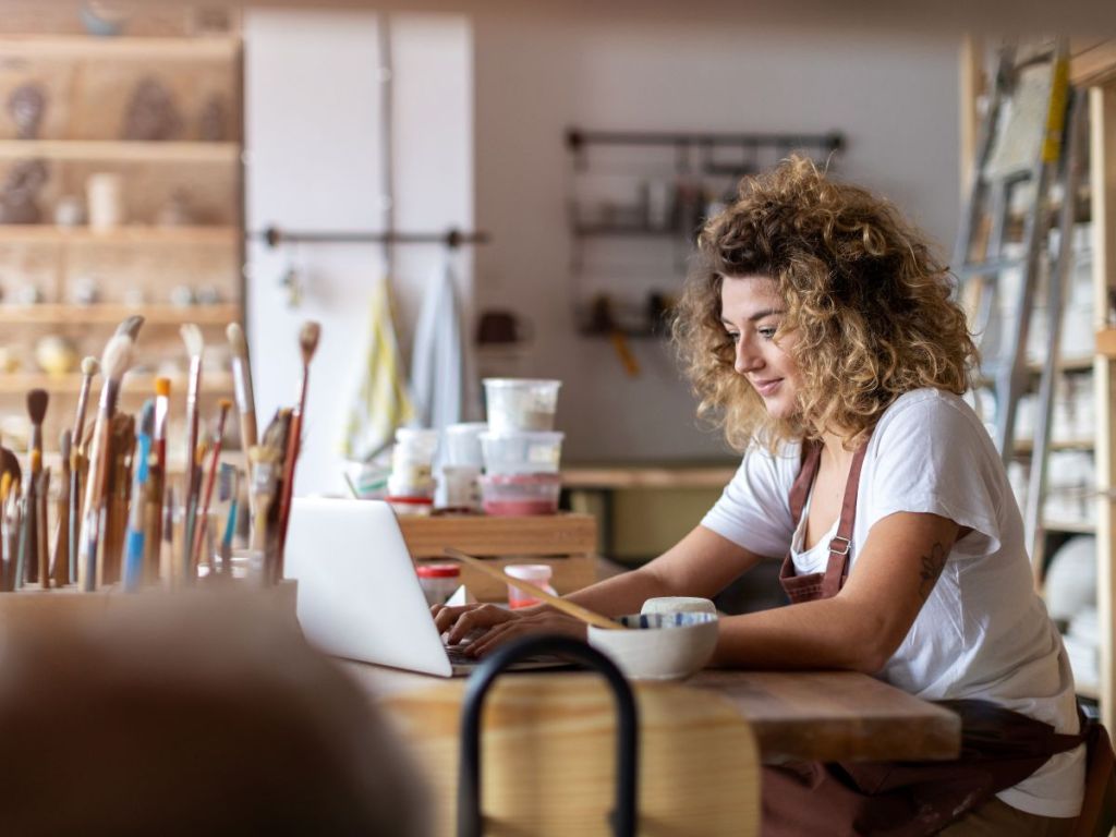 woman sitting at an art studio working on a laptop
