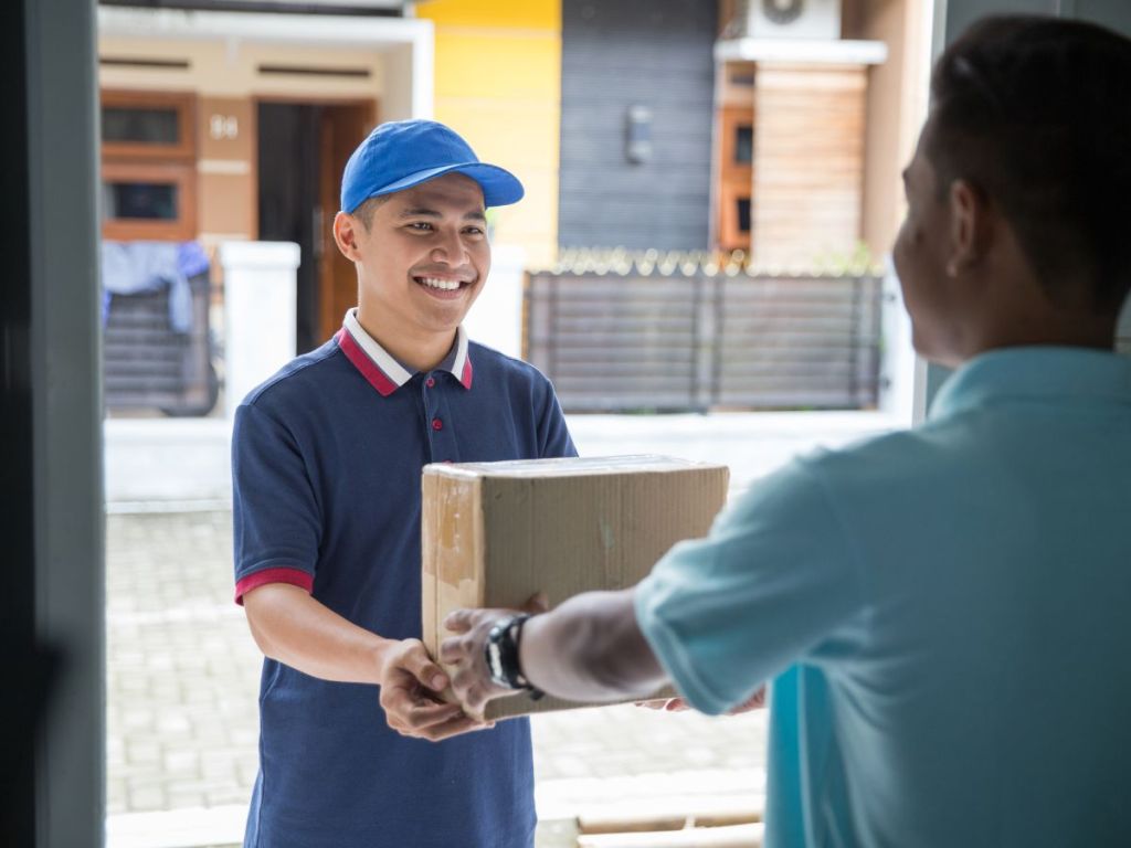 Delivery staff giving a boxed package to recipient