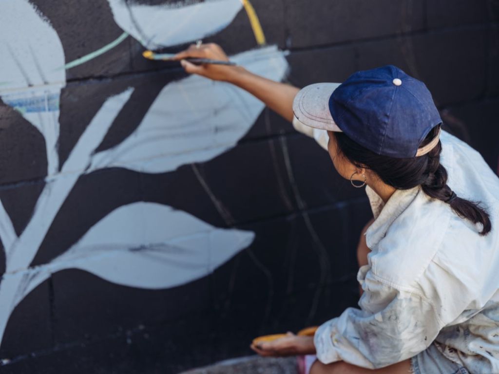 close-up of a mural artist painting blue leaves