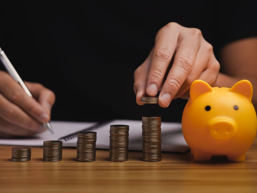 man putting coins in a piggy bank
